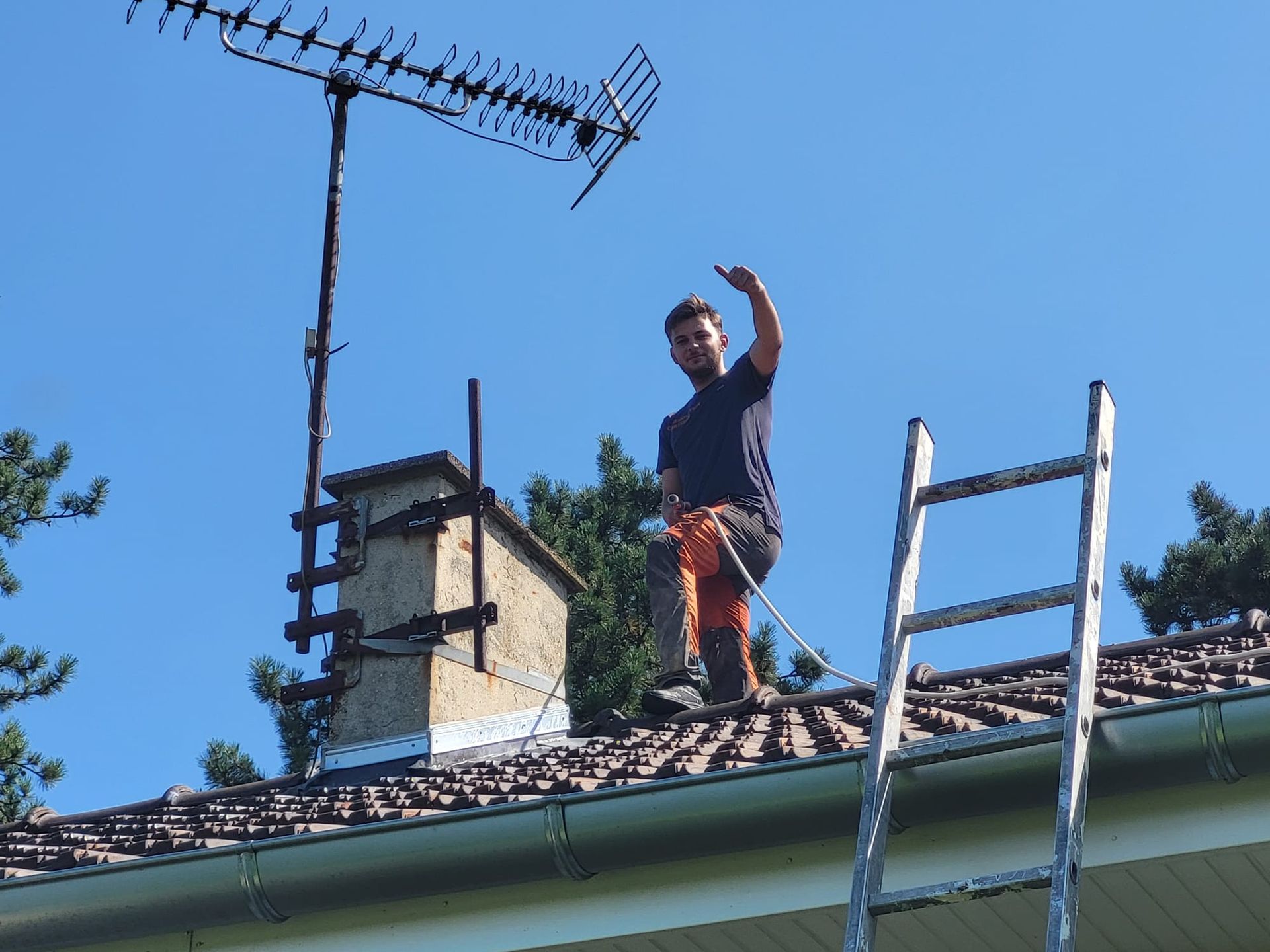Le professionnel sur le toit à côté d'un conduit de cheminée.
