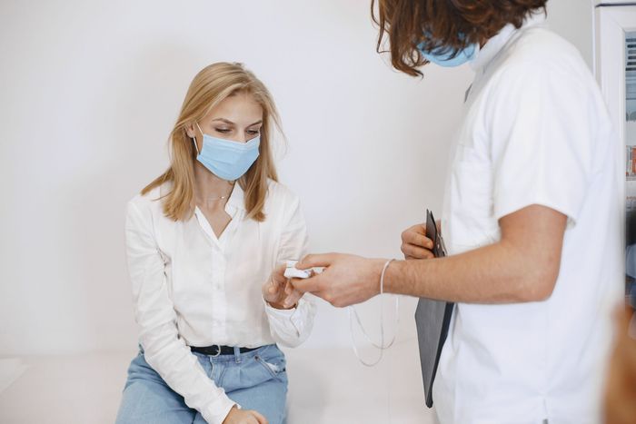Patient masqué subissant un test de dépistage par piqûre au doigt effectué par un professionnel de santé en blouse blanche