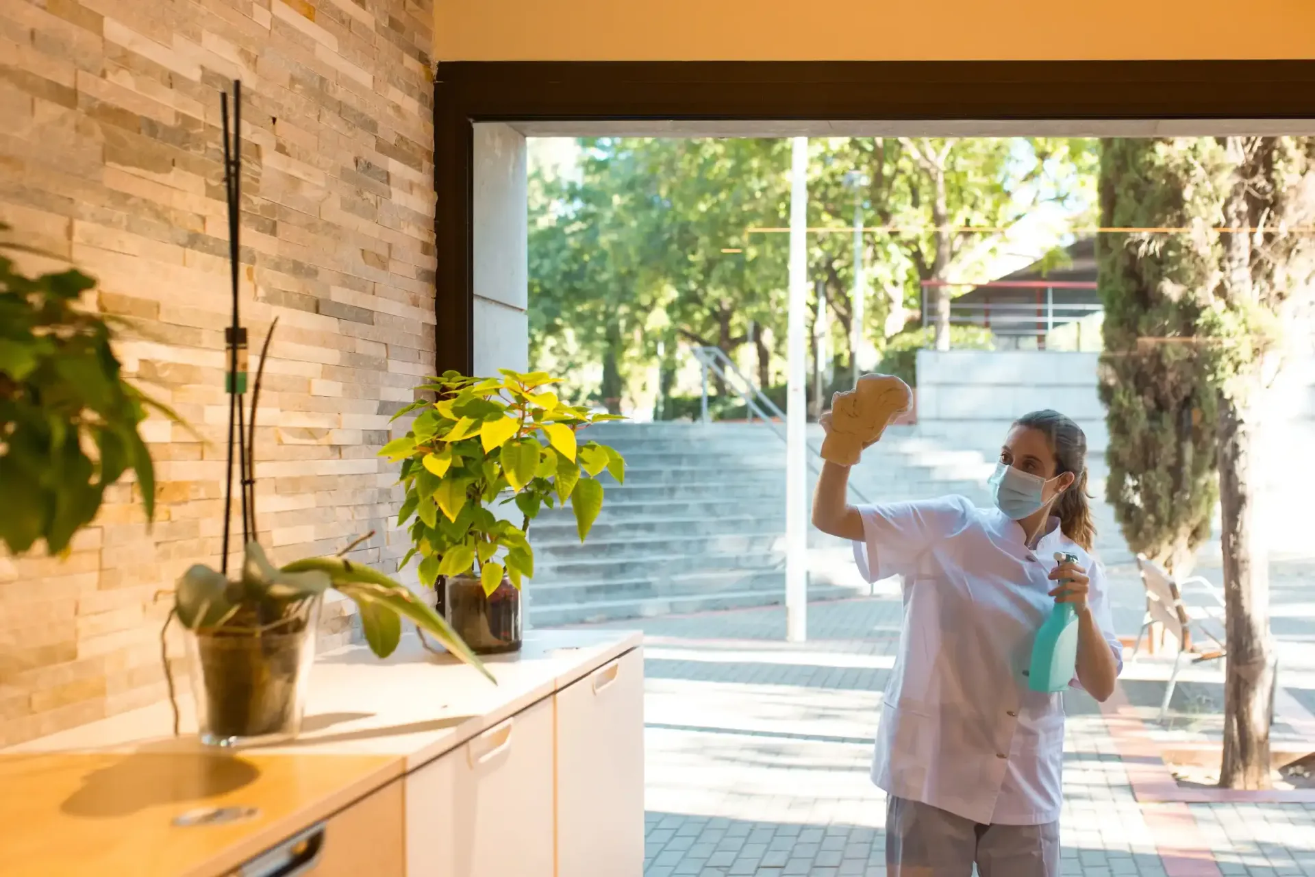 Un trabajador, con mascarilla, limpia una ventana de cristal 