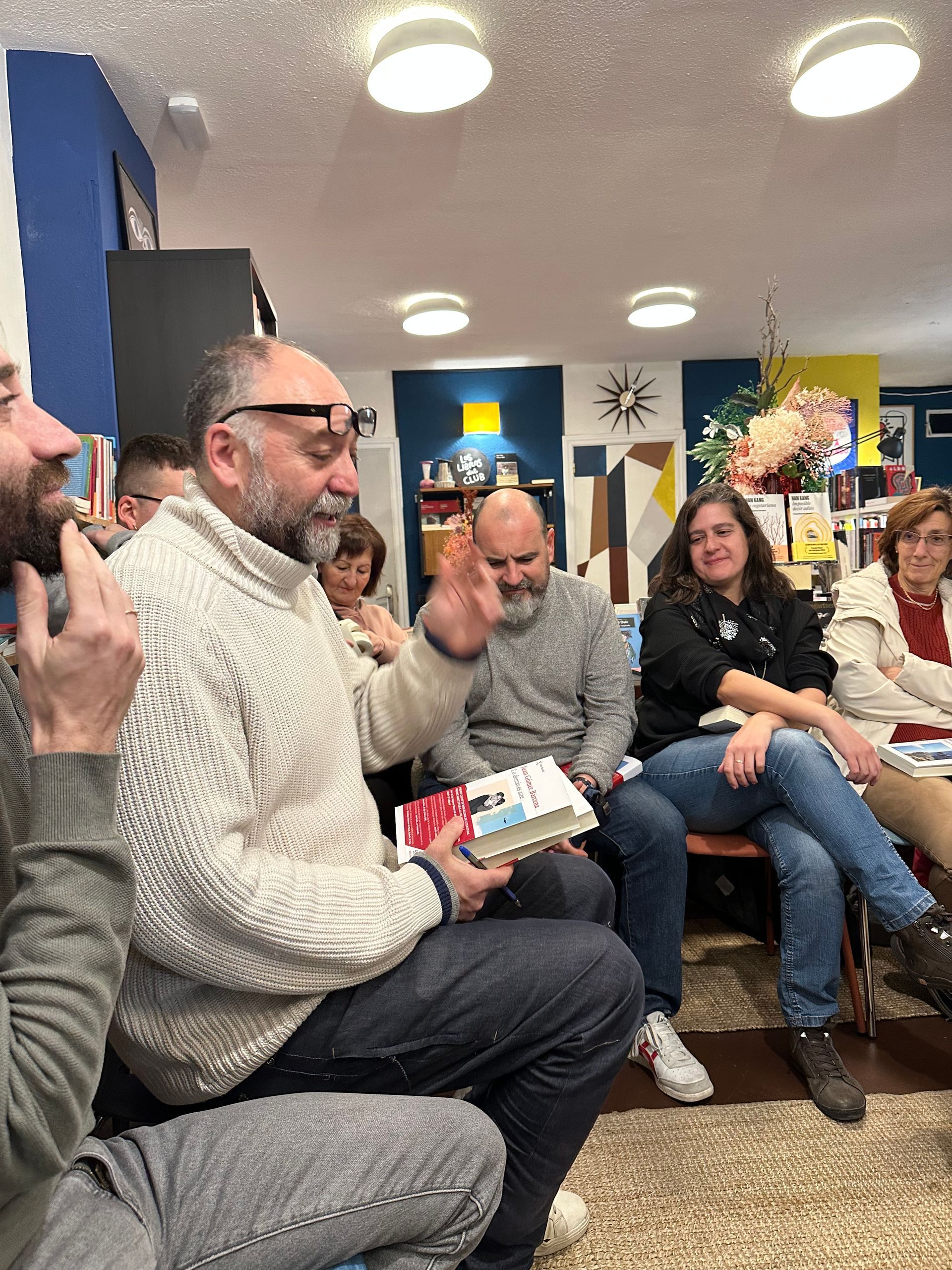 Un grupo de personas está sentada alrededor de un hombre que sostiene un libro.