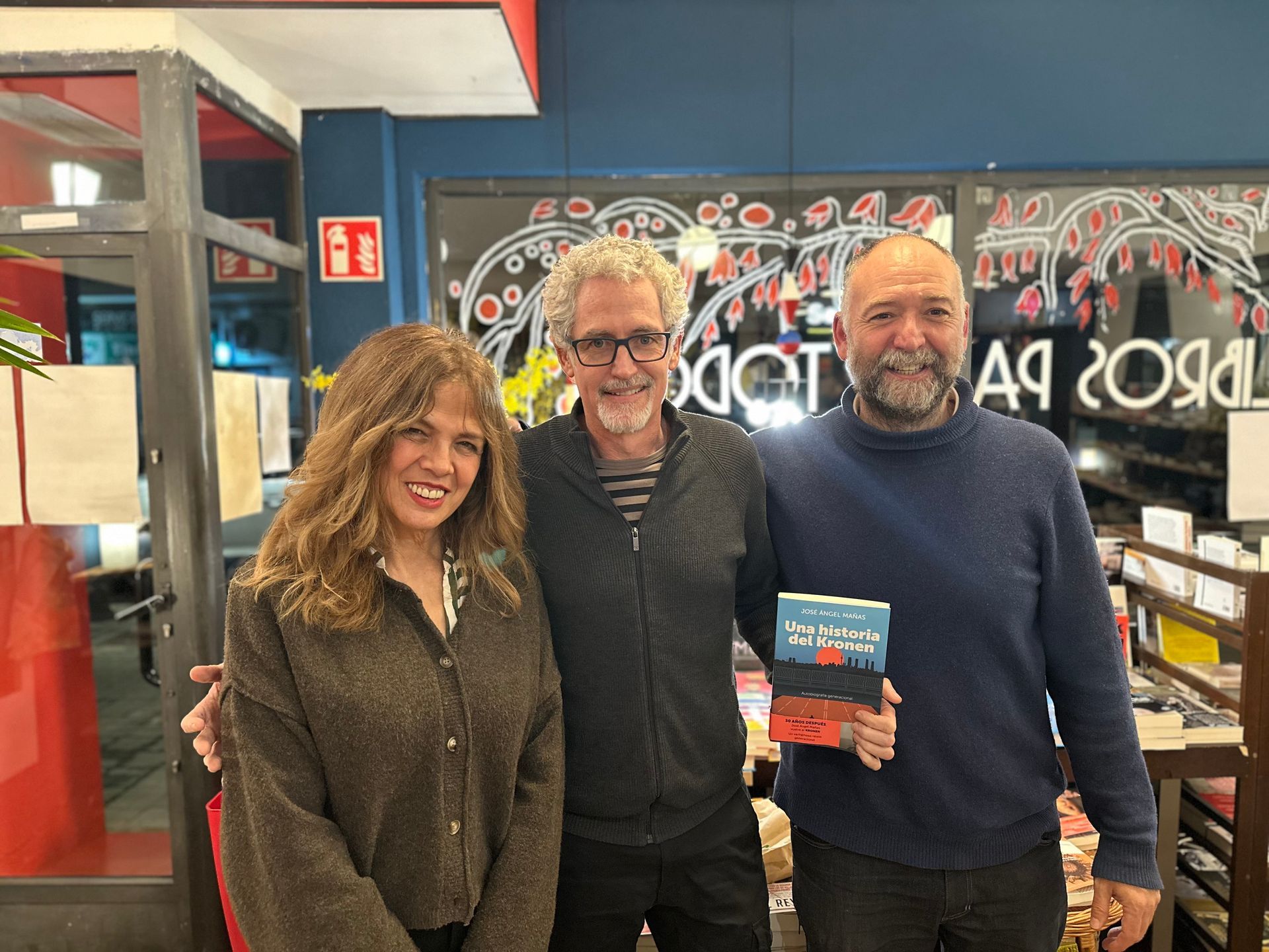 Tres personas posan para una fotografía en una biblioteca.
