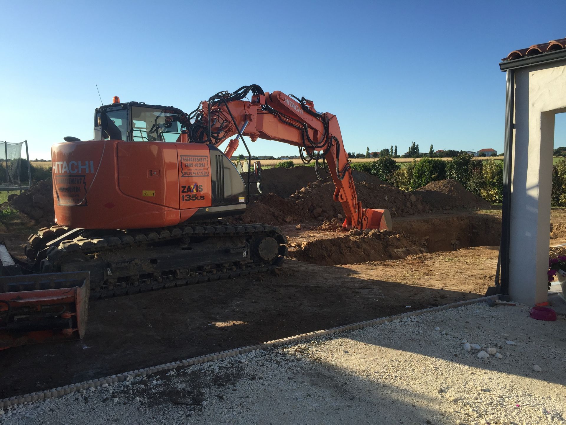 Pelleteuse orange en train de creuser un trou