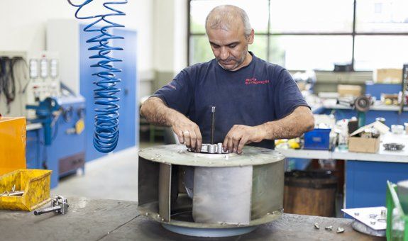 Ein Mann arbeitet in einer Fabrik an einem Ventilator.