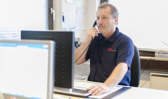 Ein Mann sitzt an einem Schreibtisch und telefoniert.