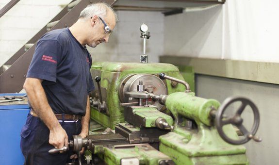Ein Mann arbeitet in einer Fabrik an einer Drehbank.