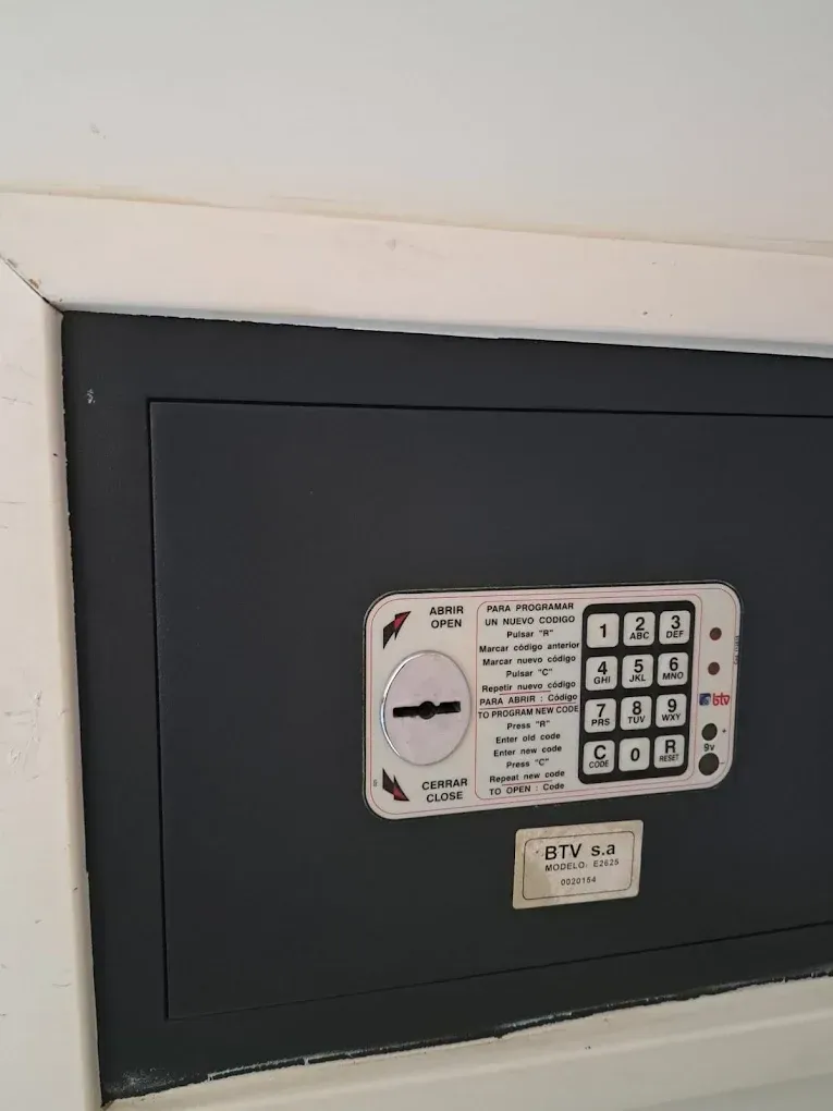 Caja fuerte de pared negra con teclado digital integrada en un hueco de techo blanco.