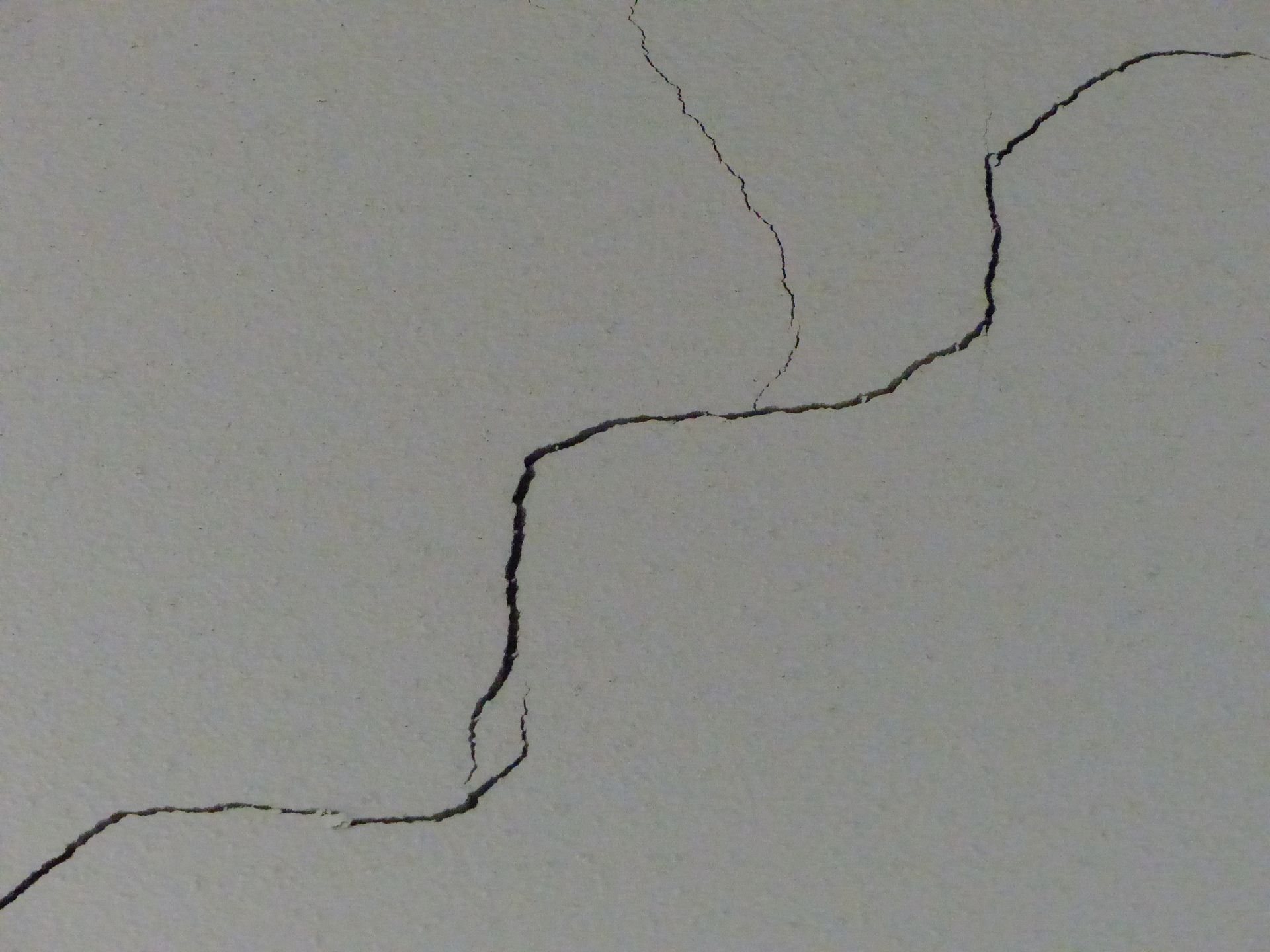 Zwei Bauarbeiter überprüfen Baupläne an einem Schreibtisch mit Schutzhelmen, Modellbau und Laptop.