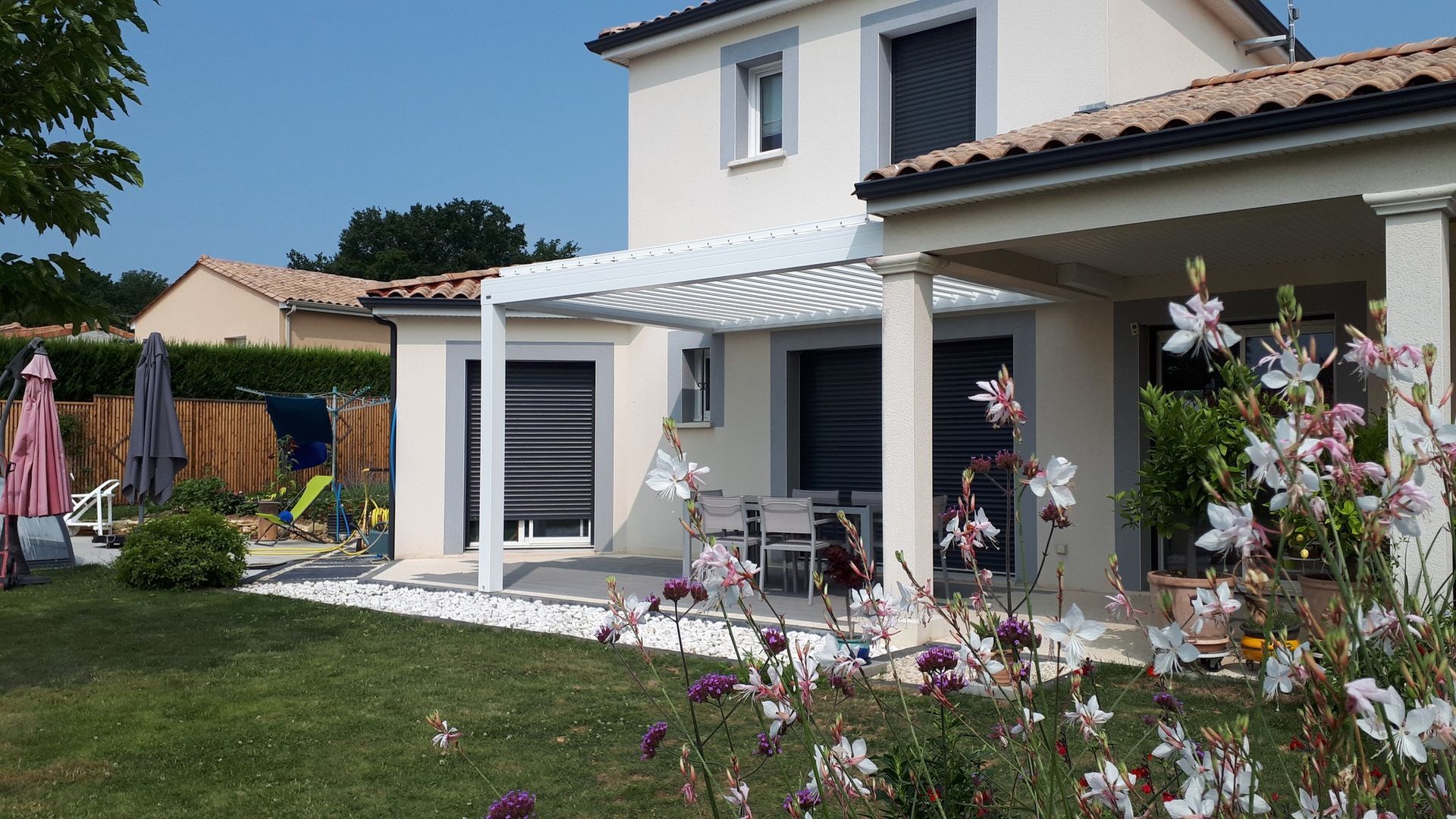 Jolie maison avec une pergola blanche sur la terrasse