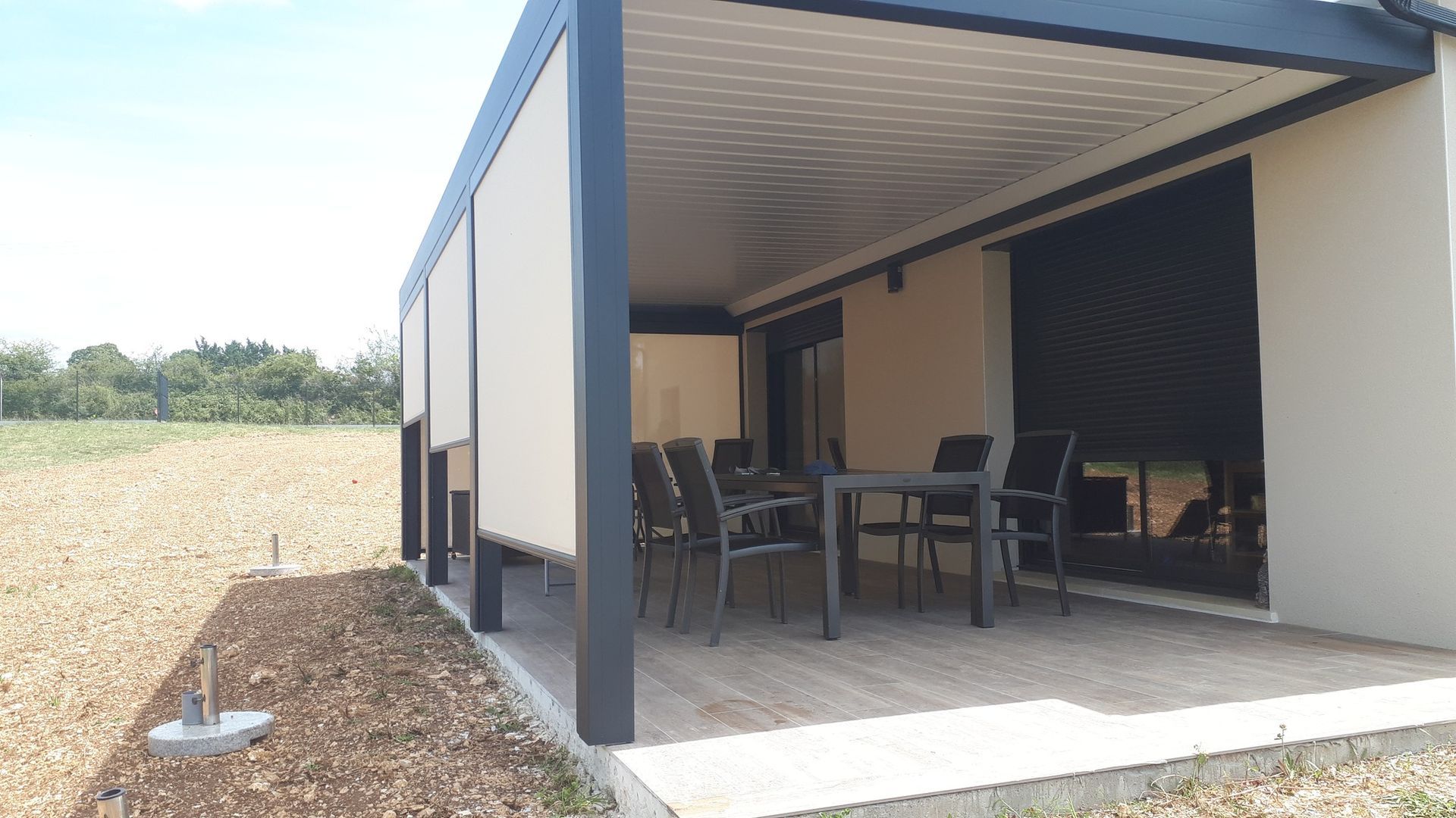 Pergola à toit fixe adossée à la façade d'une maison et un salon de jardin