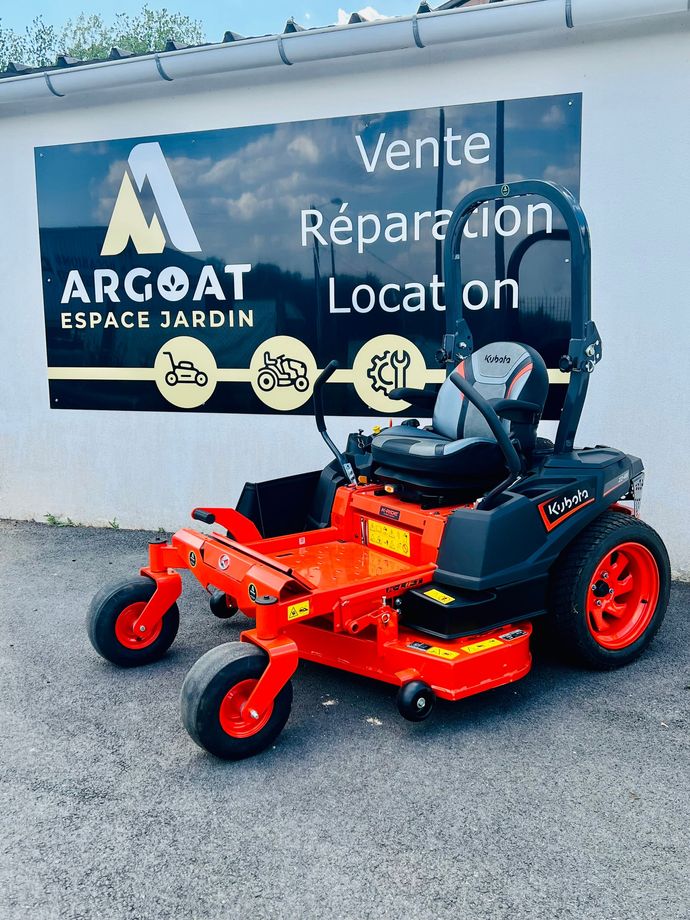 Un mécanicien travaille sur un petit moteur dans un atelier, avec un quad 