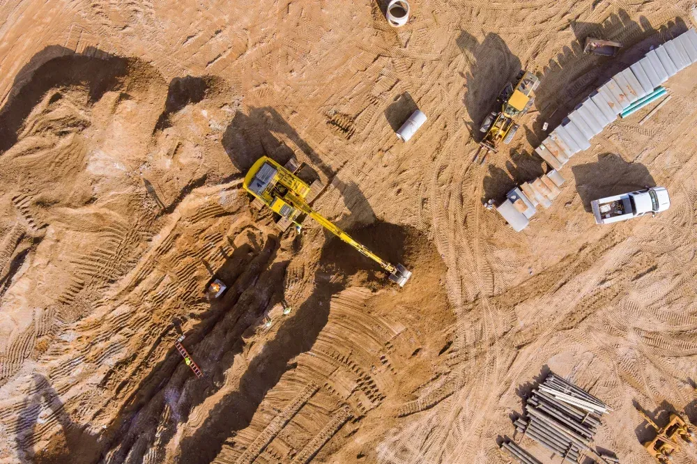 Una vista aérea de un sitio de construcción con una excavadora moviendo tierra.