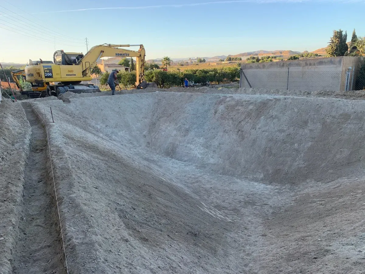 Una gran pila de tierra está siendo excavada por una excavadora amarilla.