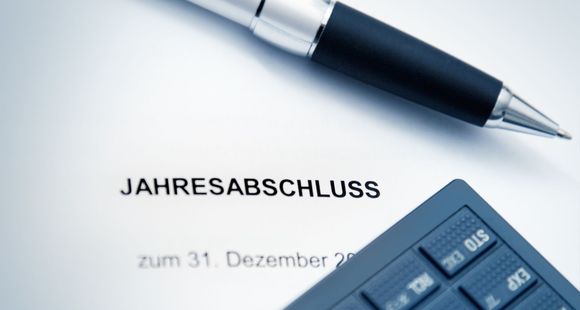 Ein Stift und ein Taschenrechner liegen auf einem Stück Papier mit der Aufschrift „Jahresabschluss“