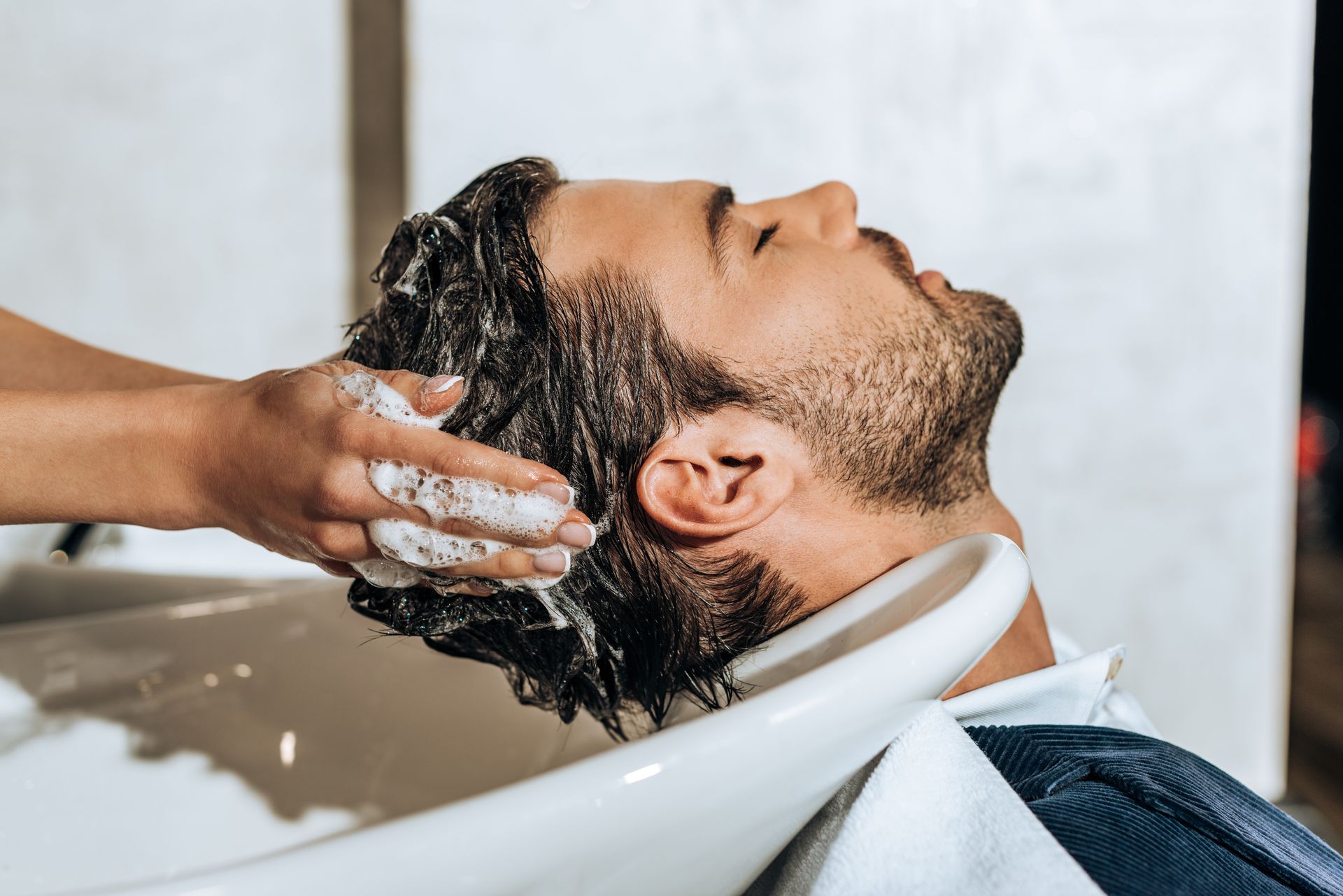 Un homme se faisant laver les cheveux par une coiffeuse.