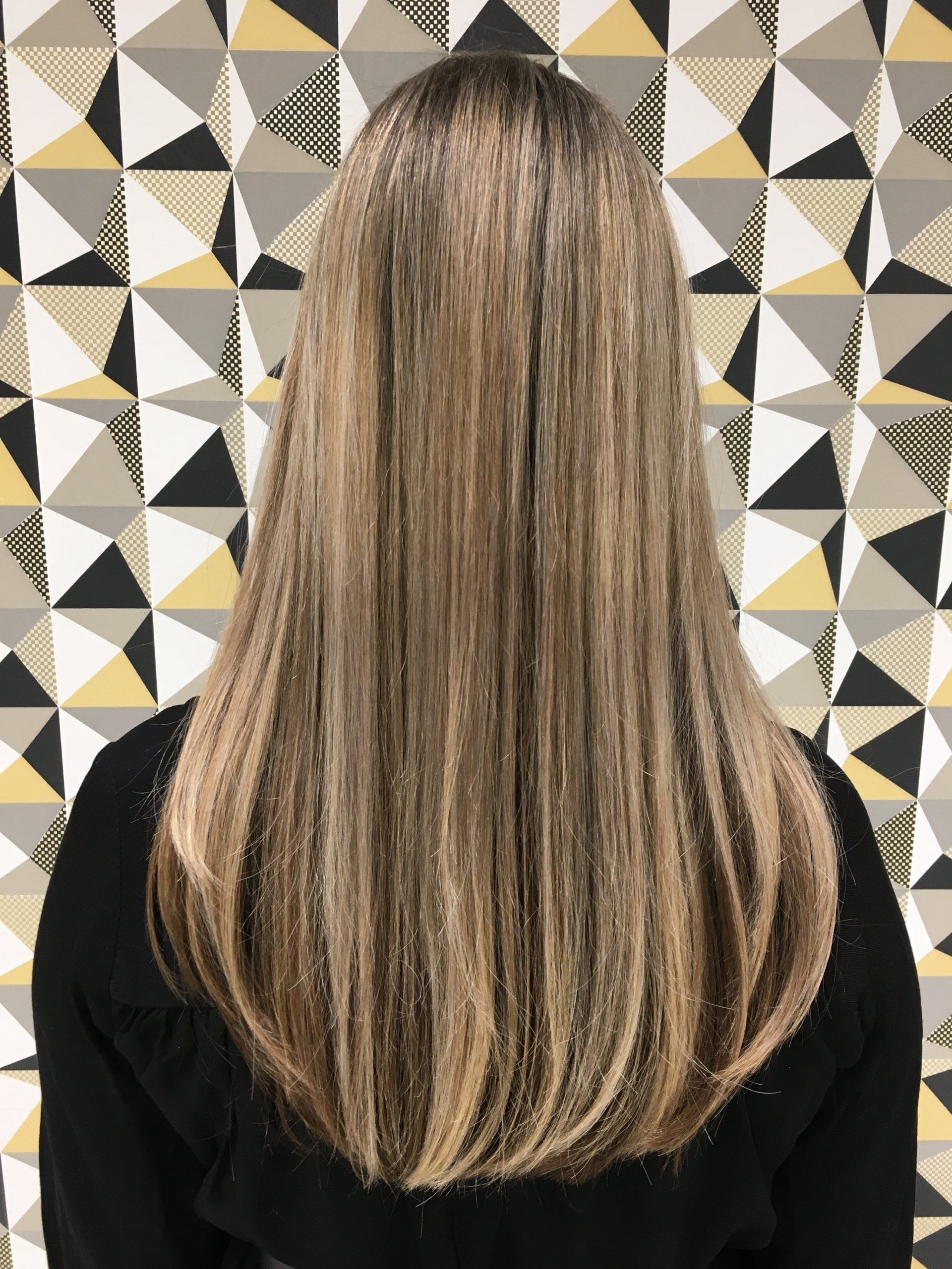 Frau mit langen blonden Haaren vor einer gemusterten Wand