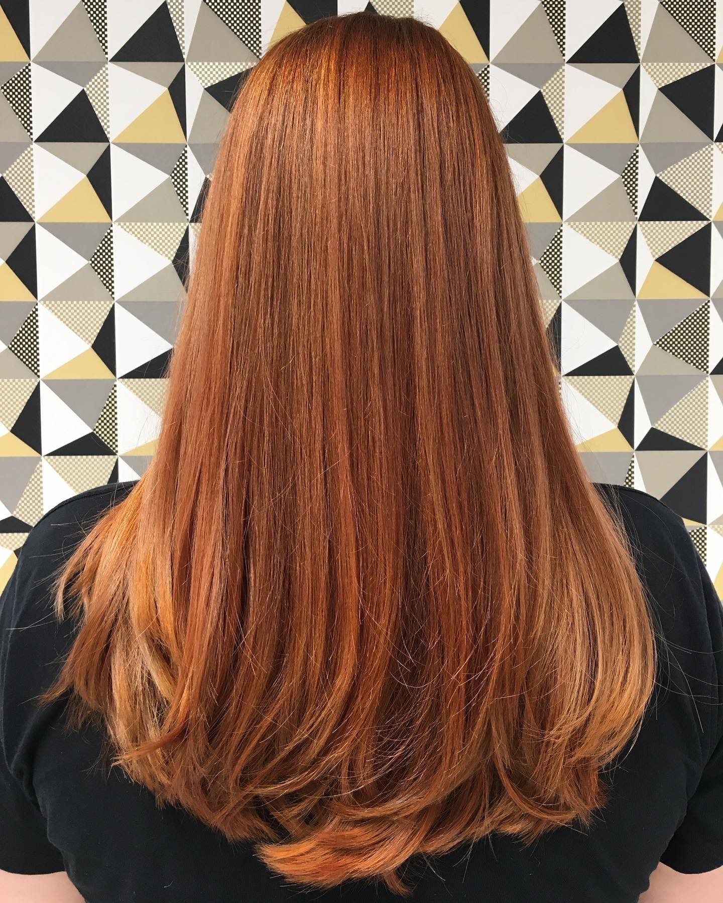 Frau mit langen roten Haaren vor einer gemusterten Wand