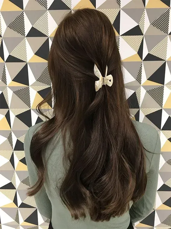 Frau mit langen braunen Haaren vor einer gemusterten Wand