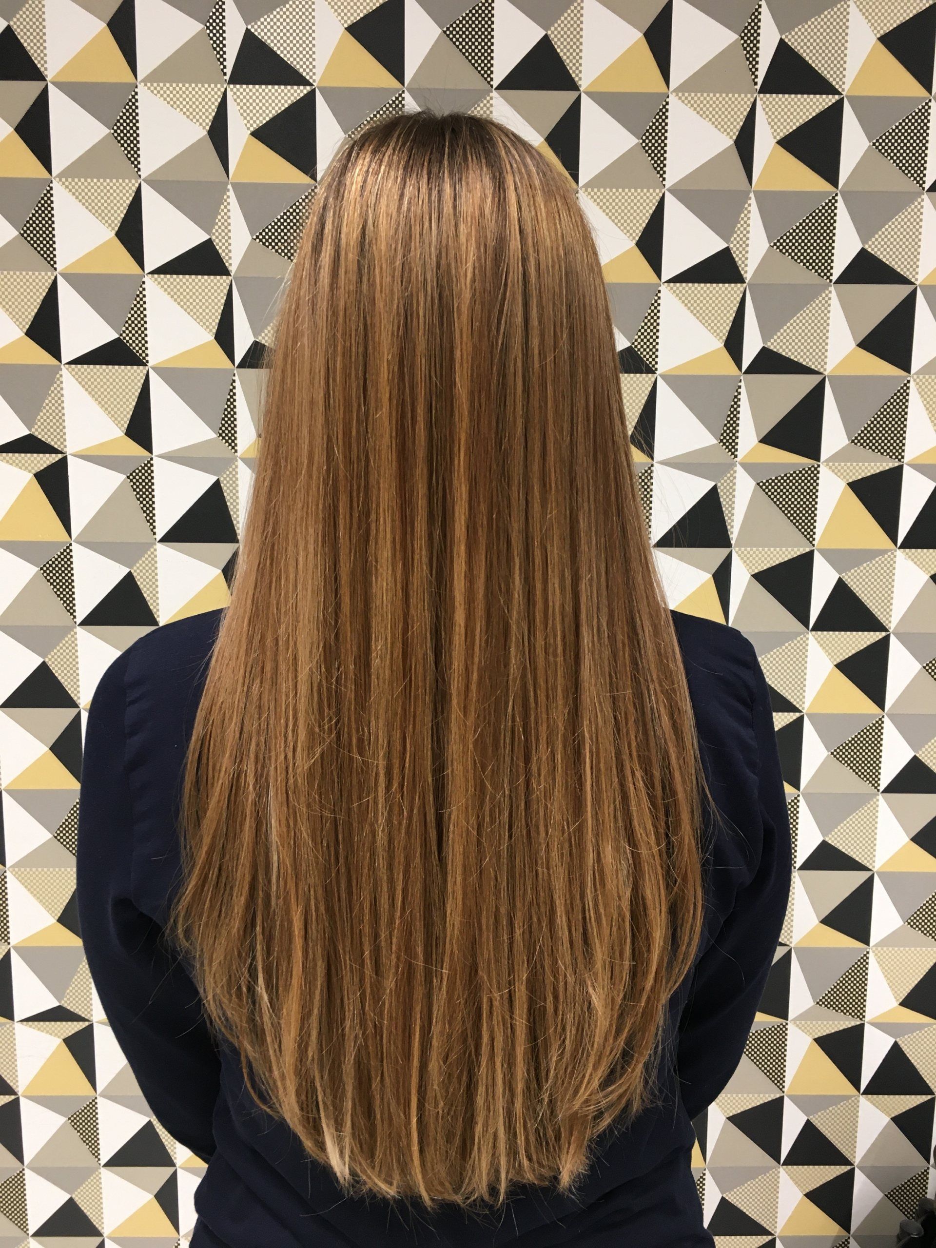 Frau mit langen blonden Haaren vor einer gemusterten Wand