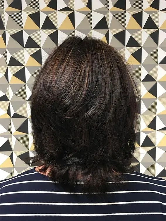 Frau mit mittellangen braunen Haaren vor einer gemusterten Wand