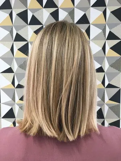 Frau mit mittellangen blonden Haaren vor einer gemusterten Wand