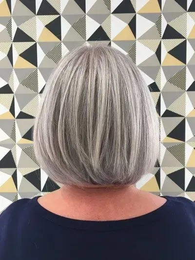 Frau mit mittellangen grauen Haaren vor einer gemusterten Wand