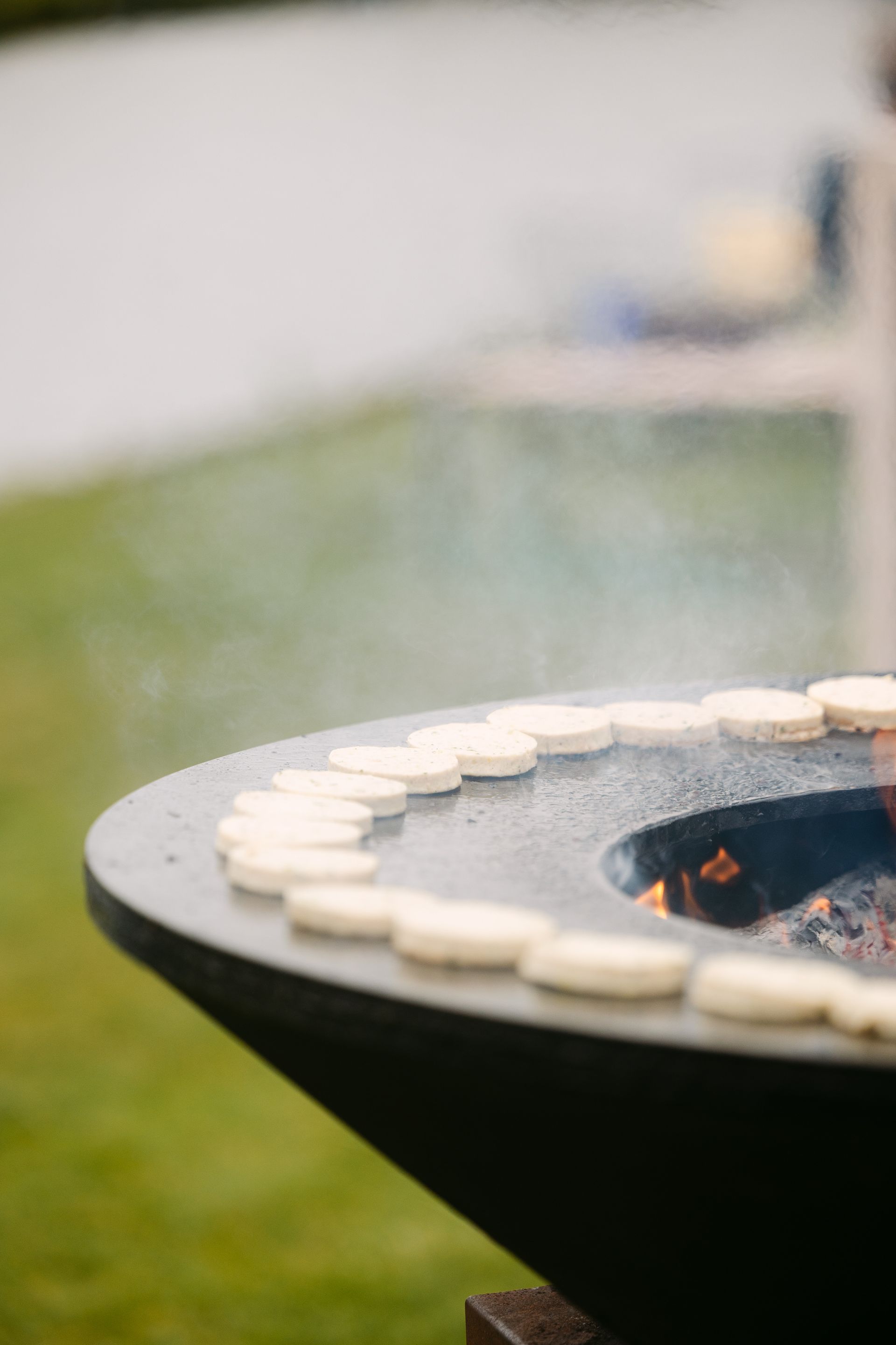 Dek de eettafel op een rustiek terras met borden, glazen, kaarsen en een kerstboom op de achtergrond.