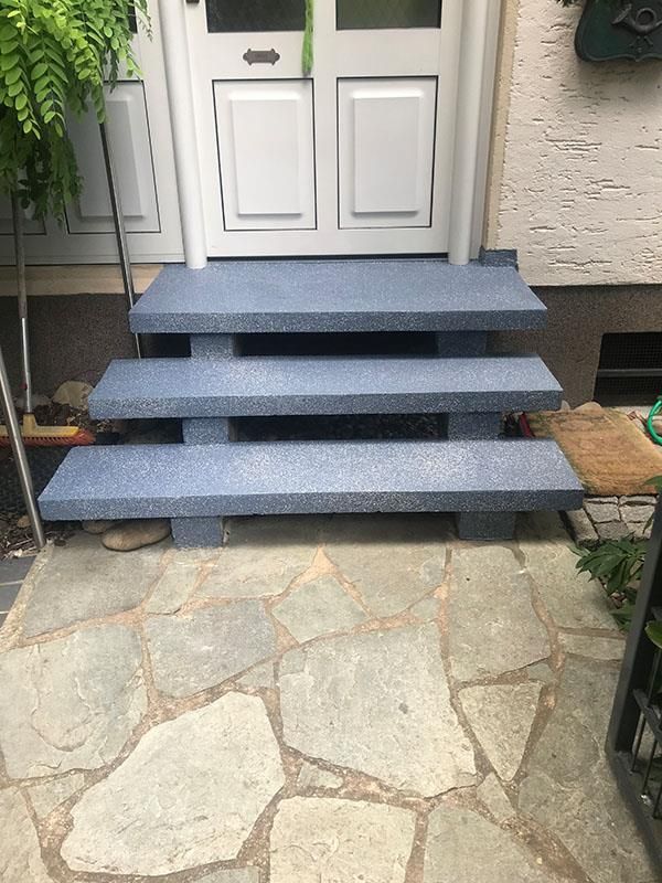 Eine blaue Treppe führt hinauf zu einer weißen Tür.