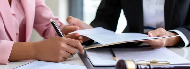 Manos escribiendo en cuadernos durante una reunión de negocios en una mesa.