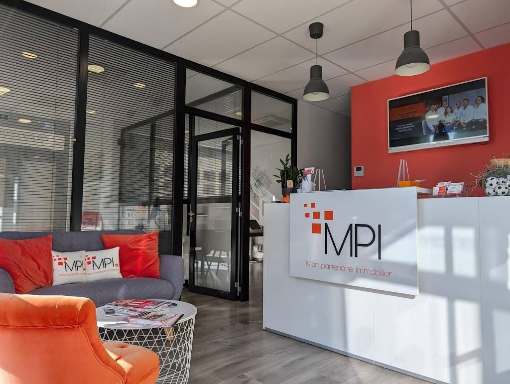 L'accueil de l'agence avec un comptoir, un canapé, un fauteuil et une table basse.