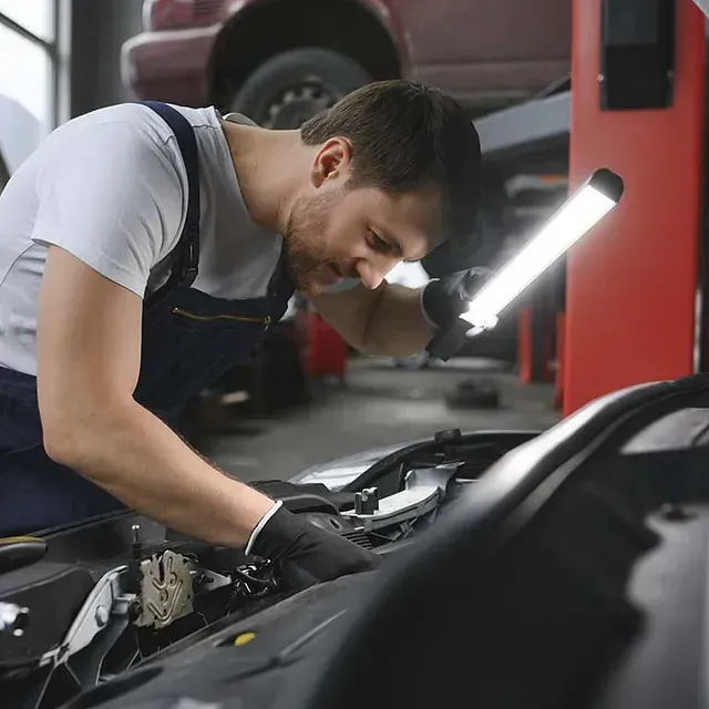 Un hombre está trabajando en el motor de un coche en un garaje.