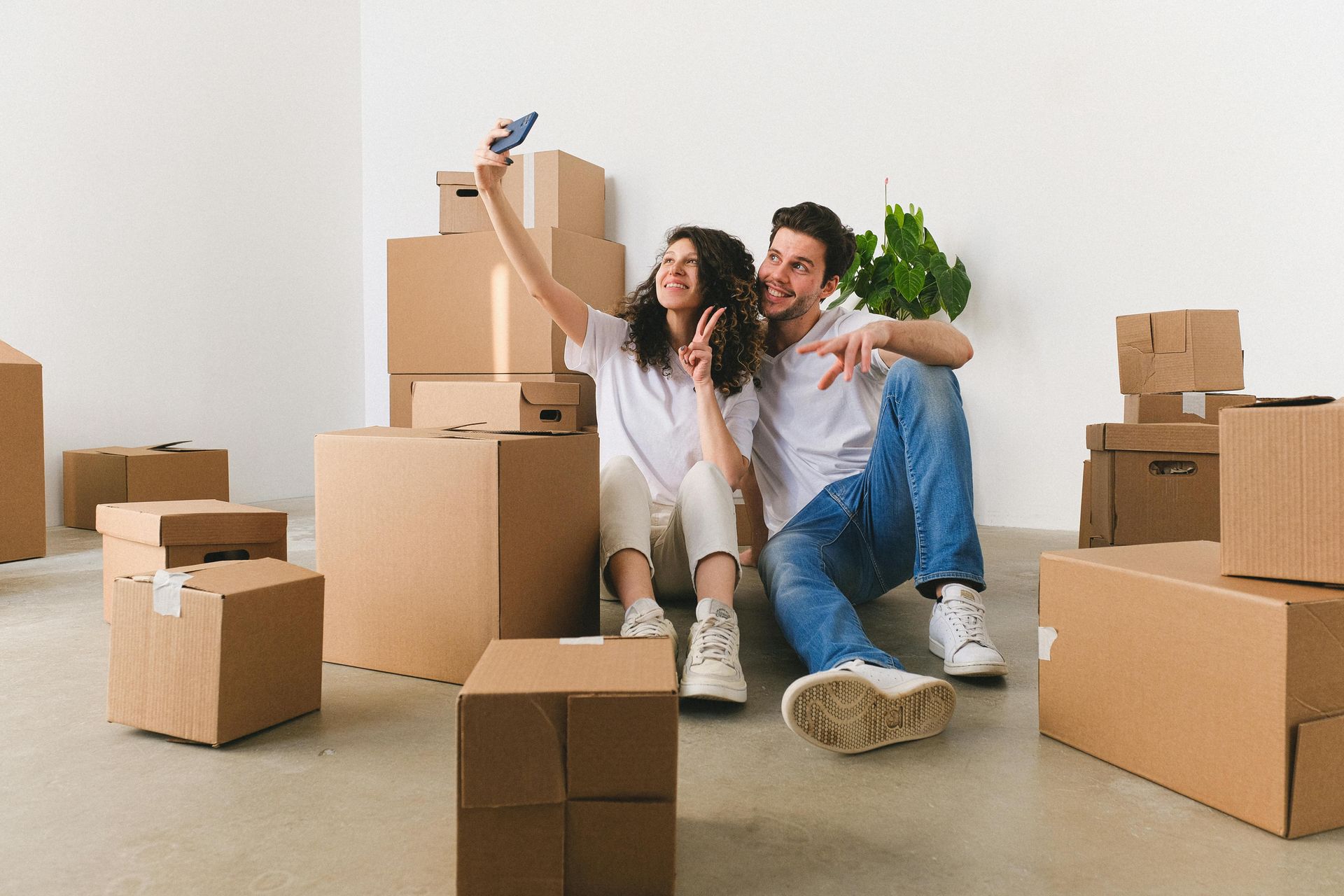 Pareja tomándose un selfie en su nueva casa, rodeada de cajas de mudanza.