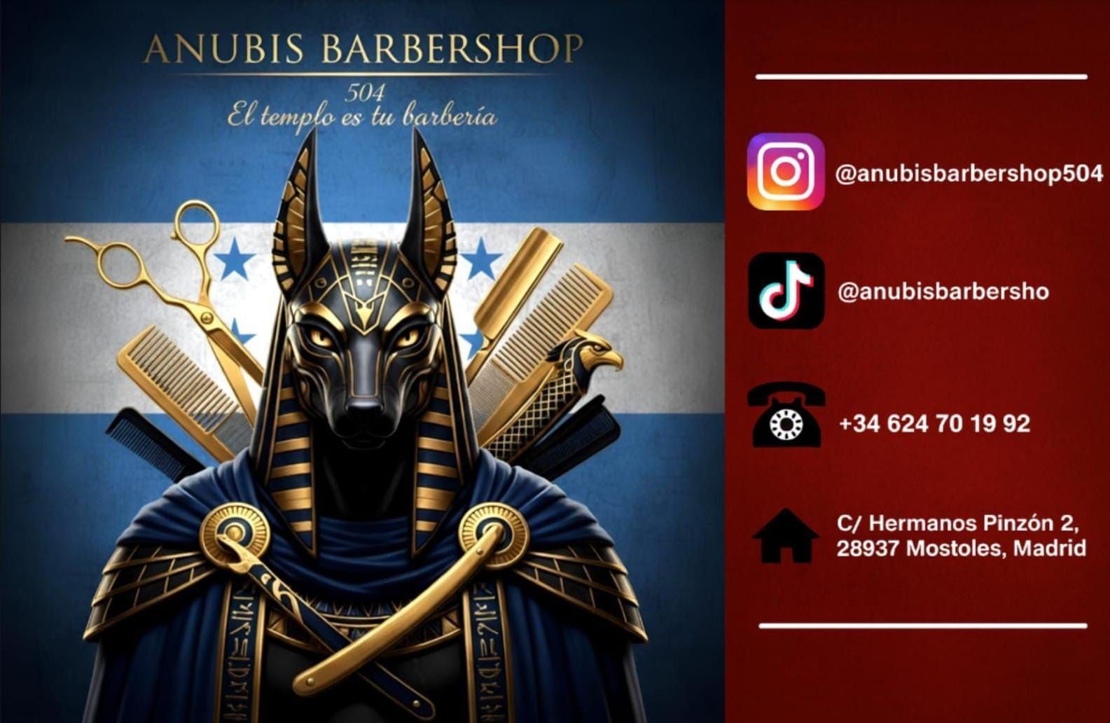Tarjeta de presentación: Barbería Anubis con figura de Anubis, herramientas de barbería, fondo de bandera, información de contacto.