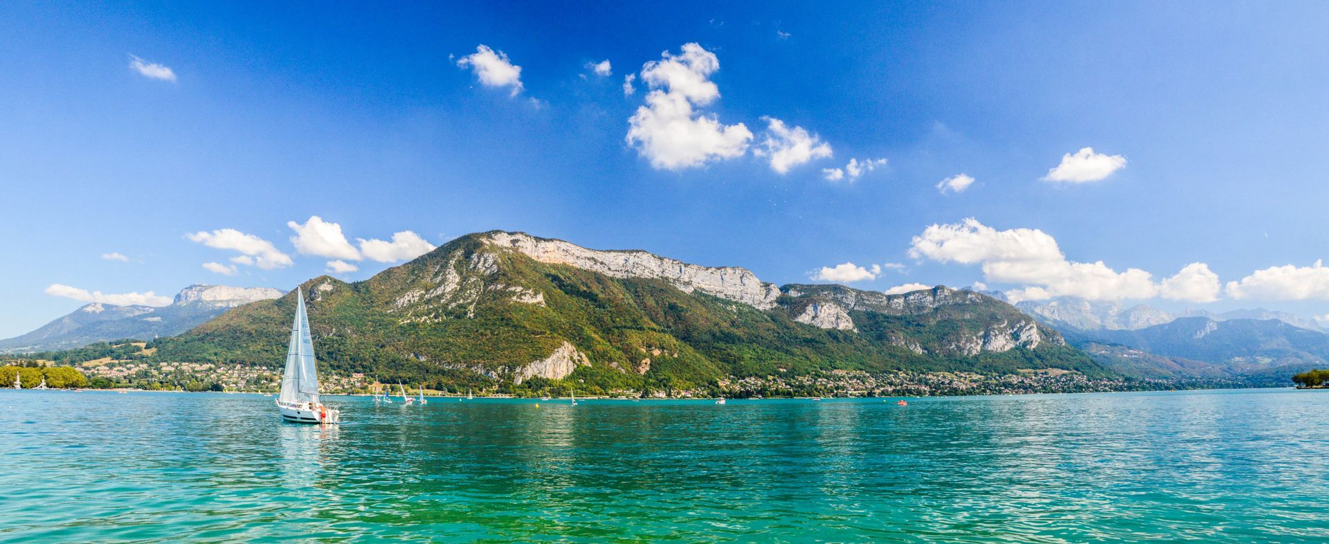 Le lac d'Annecy avec un voilier et des montagnes en fond