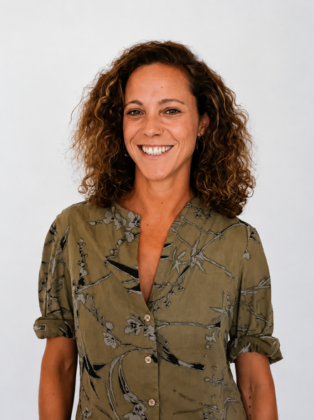 Mujer sonriente con blusa estampada de pie sobre un fondo blanco liso.