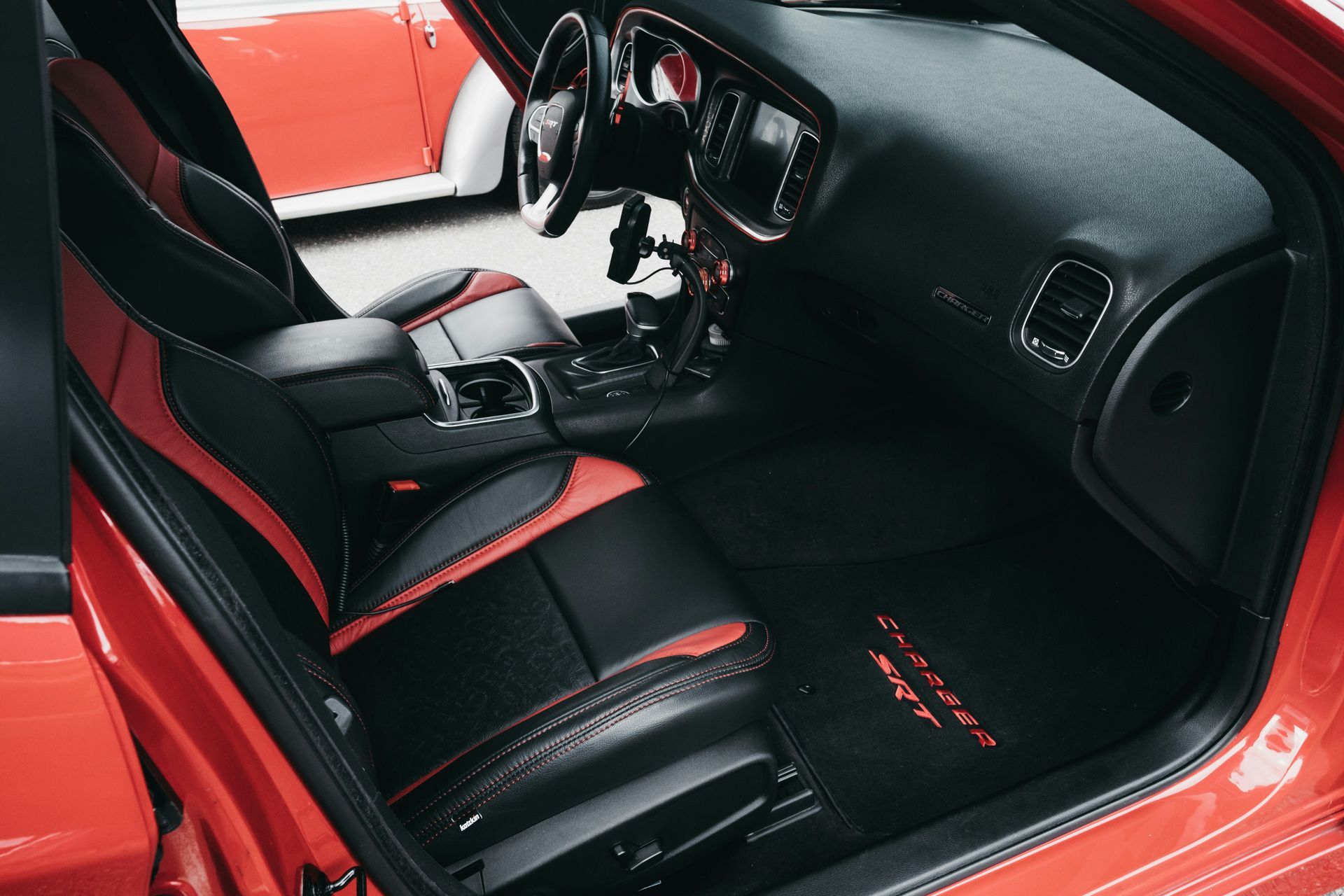 Interior de un Dodge Charger rojo con asientos de cuero bicolor en negro y rojo y un salpicadero negro.