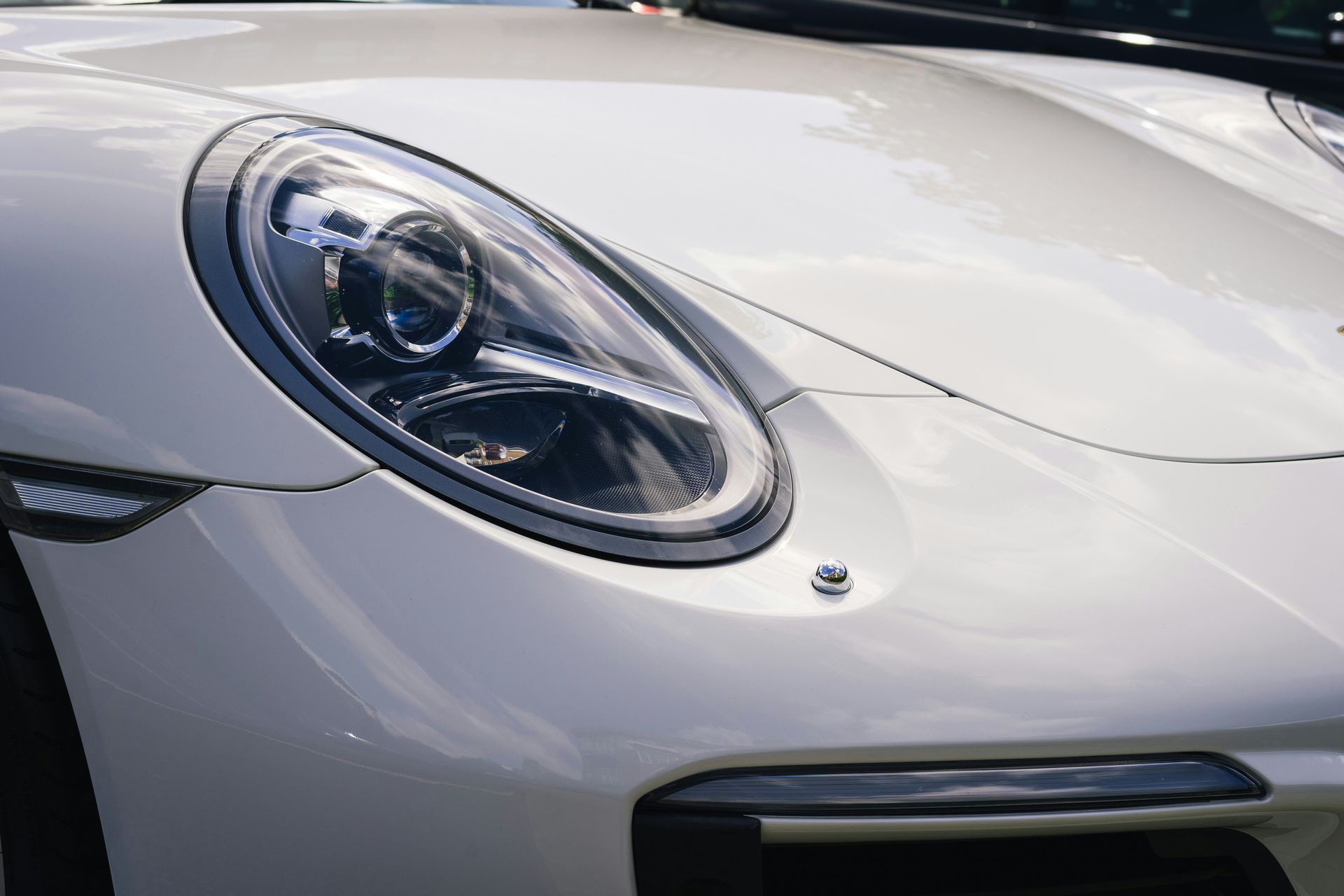 Un coche azul brillante aparcado sobre cemento junto a un cubo de metal en un día soleado.