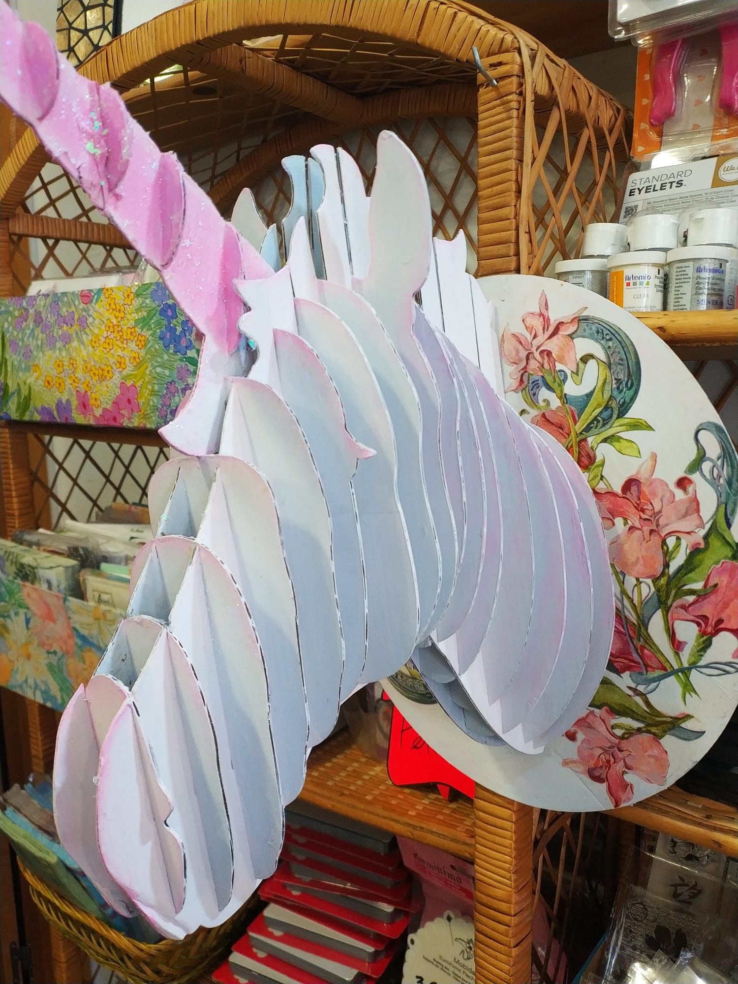 Una cabeza de unicornio de papel está sentada encima de un estante de mimbre.