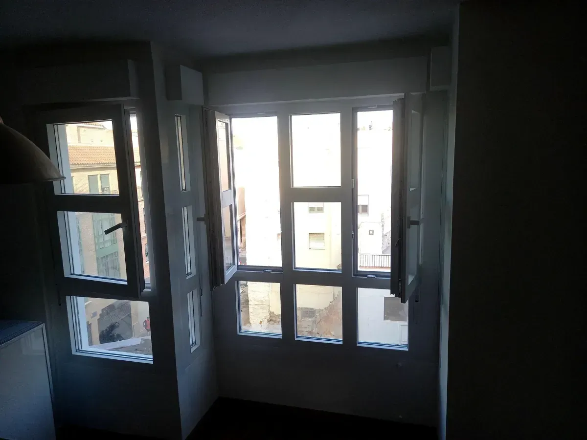 Ventanas de un edificio, luz solar entrando a través de los paneles de vidrio y contraventanas abiertas