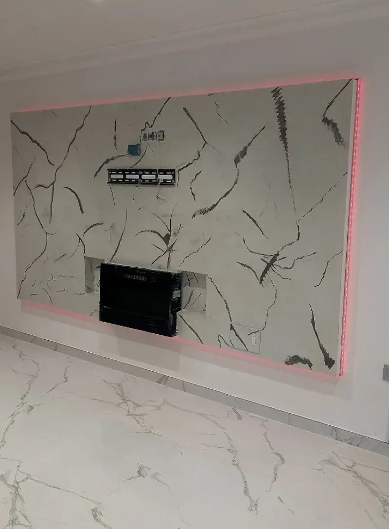 Una pared moderna con acento y luces LED rosas, con un televisor y una consola multimedia. Suelo de mármol.