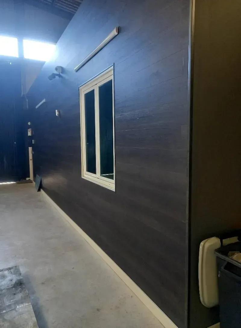 Exterior de edificio con paneles de color marrón oscuro y una ventana con marco blanco.