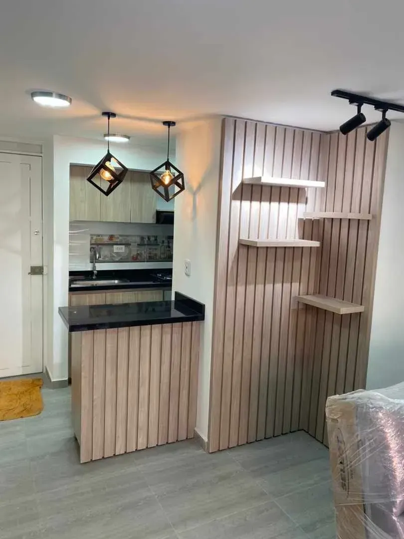 Cocina con encimera y estantes de madera, luces de techo y una combinación de colores neutros.