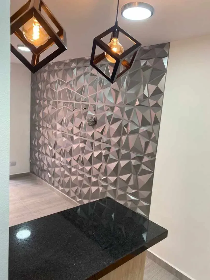 Habitación moderna con pared geométrica, encimera negra y luces colgantes en forma de cubo.