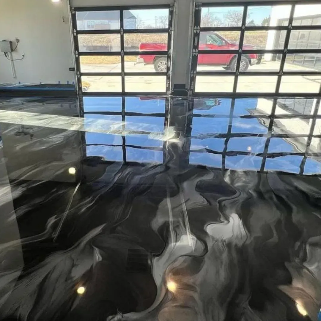 Piso epoxi en tonos negro, gris y blanco con grandes ventanales que reflejan un camión rojo afuera.