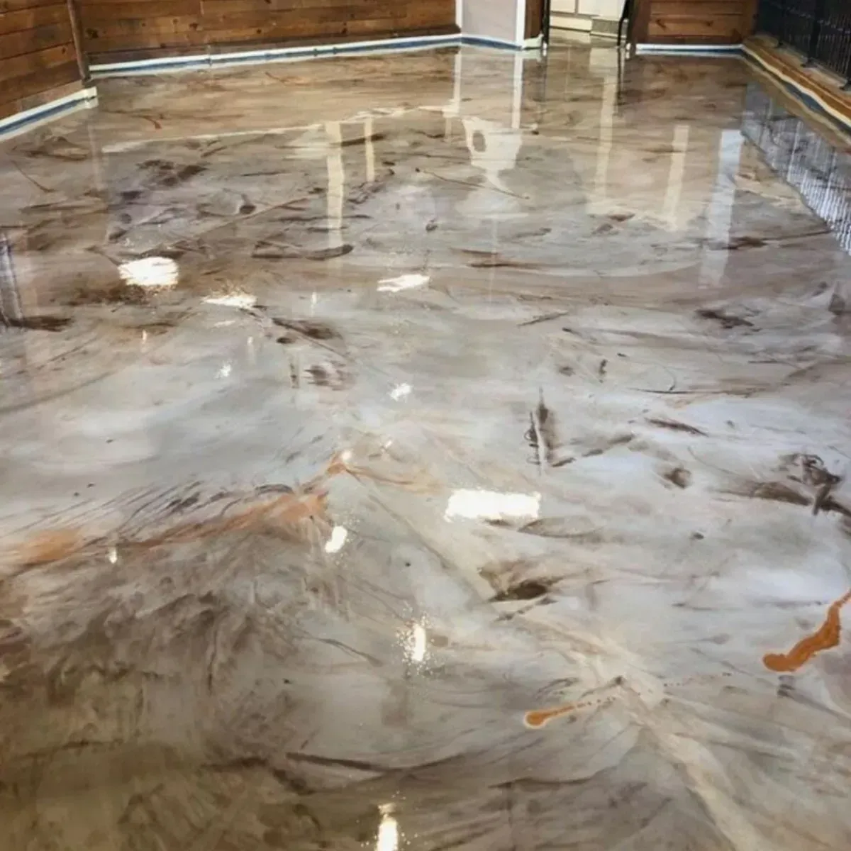 Piso epoxi metálico con remolinos marrones y tostados que reflejan la habitación.