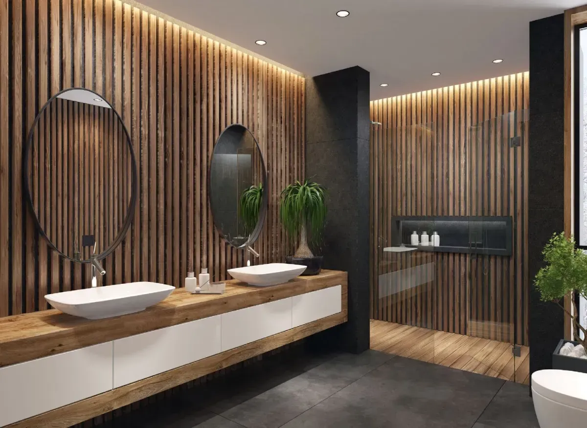 Baño moderno con paneles de madera, dos espejos ovalados, lavabos dobles y ducha de cristal.