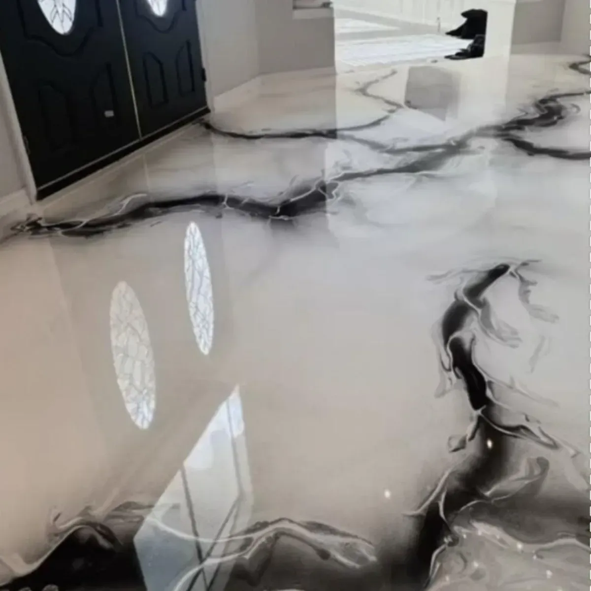 Piso de epoxi en blanco y negro con patrones en espiral en una casa, que refleja la luz natural.