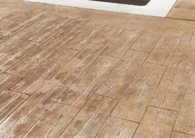 Patio de hormigón estampado con diseño de vetas de madera en tonos marrones.