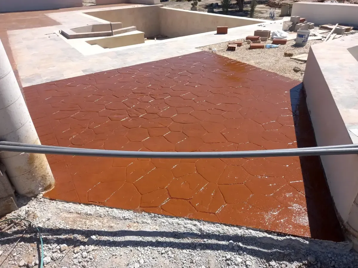 Patio de hormigón con diseño hexagonal rojo en construcción al aire libre.