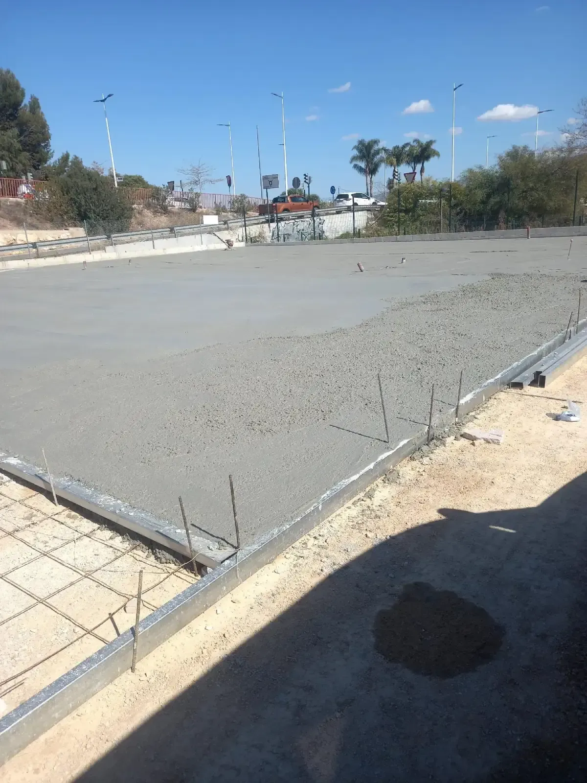 Losa de hormigón recién vertida en una obra en construcción, con estructura metálica y refuerzo visibles.