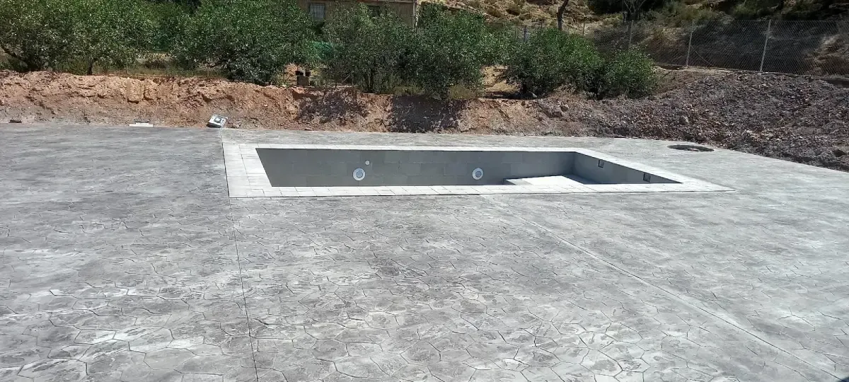Una piscina de hormigón sin terminar en un entorno al aire libre con hormigón rugoso a su alrededor.